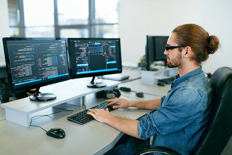 编程. Man Working On Computer In IT Office, Sitting At Desk Writing Codes. Programmer Typing Data Code, Working On Project In Software Development 公司. 高质量图像.